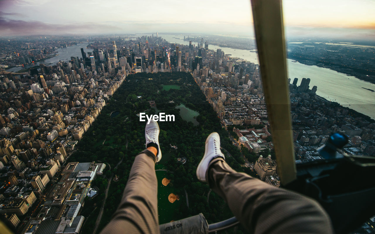 Low section of man sitting in helicopter over buildings in city