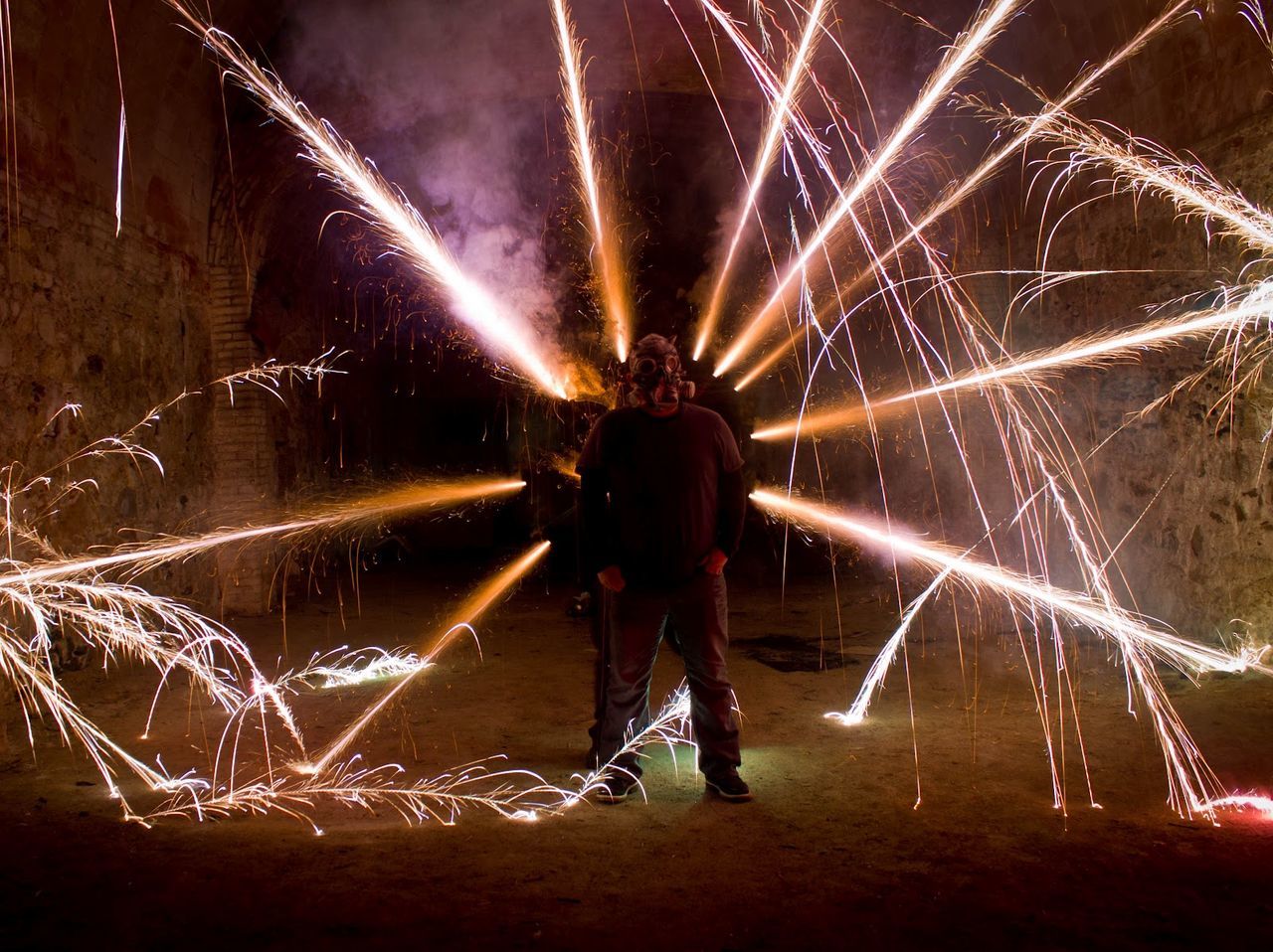 Man wearing gas mask standing amidst firework sparks