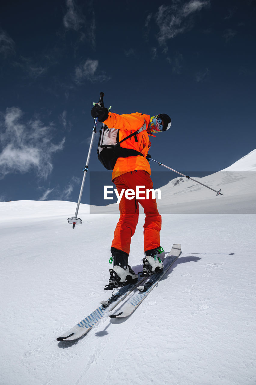 Wide angle young male athlete skier in a ski tour on skis on the background of snow-capped mountains