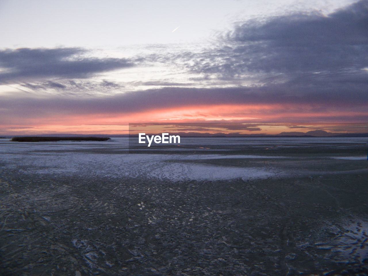 Scenic view of sea against cloudy sky at sunset