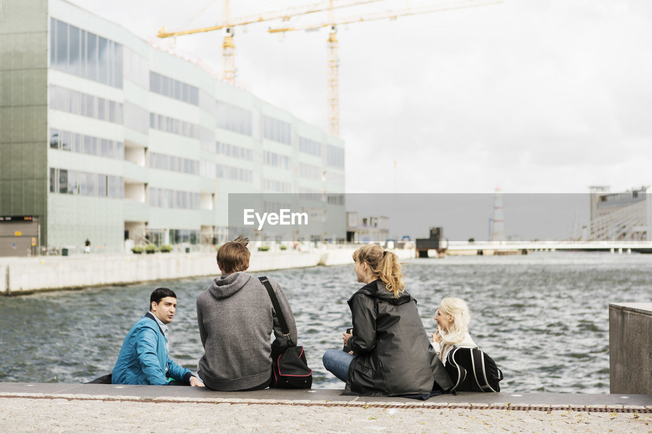 Young friends sitting on steps by river