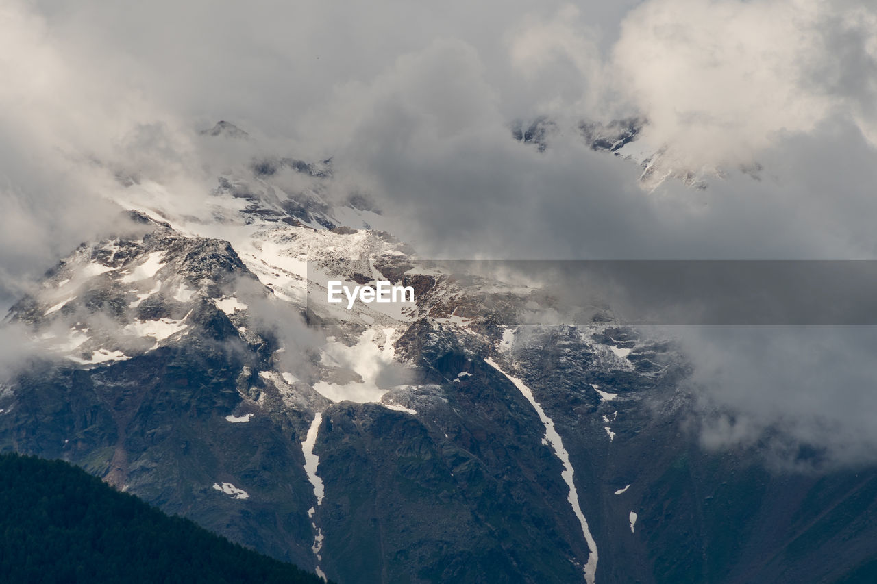 Snow capped peaks of cloud shrouded rocky mountains