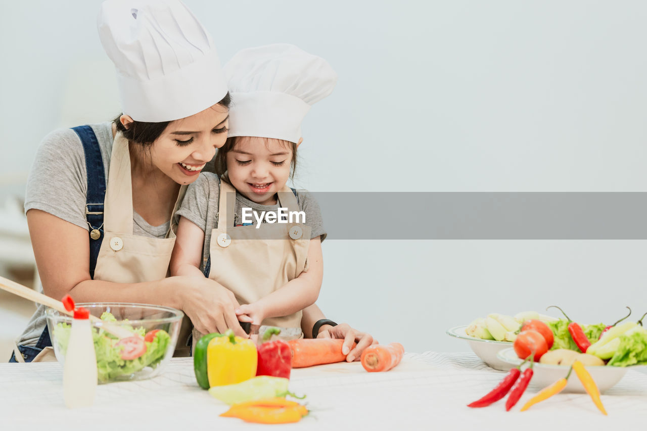 Mother and daughter preparing food on table