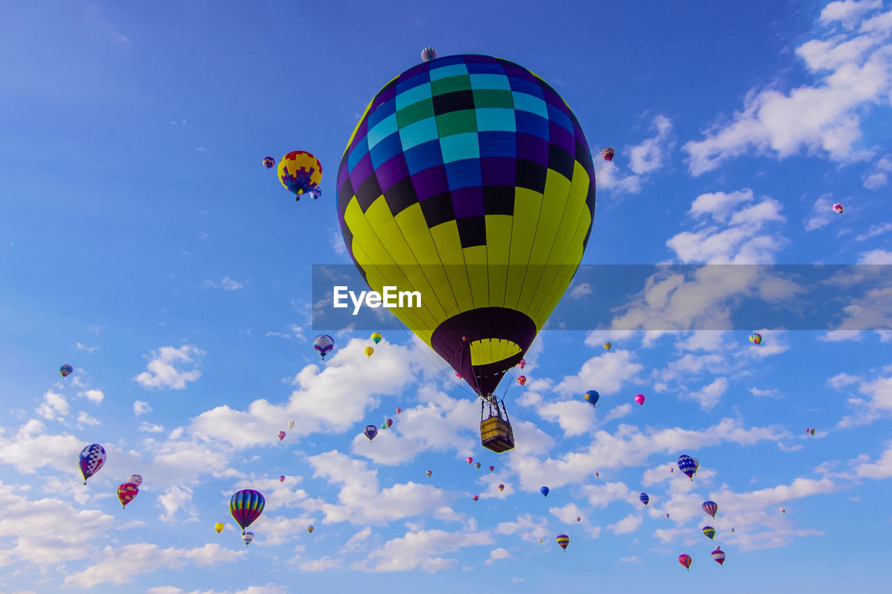Low angle view of hot air balloons flying against blue sky