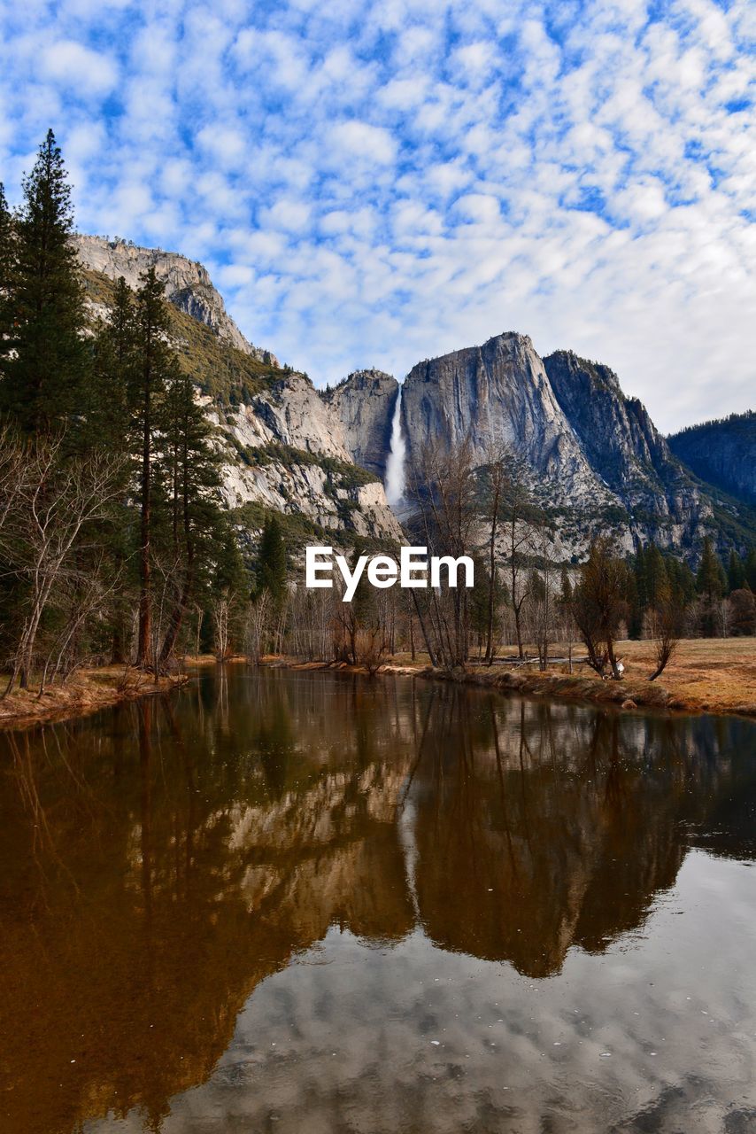 REFLECTION OF MOUNTAIN IN LAKE AGAINST SKY