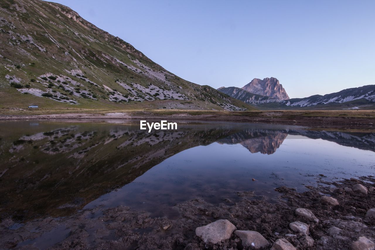 Scenic view of lake and mountains against clear sky during sunset