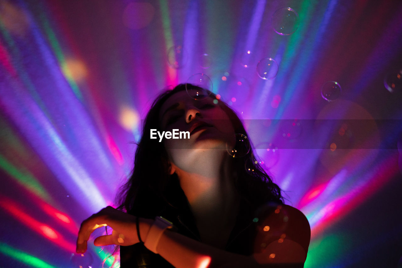 Close-up of woman in illuminated nightclub