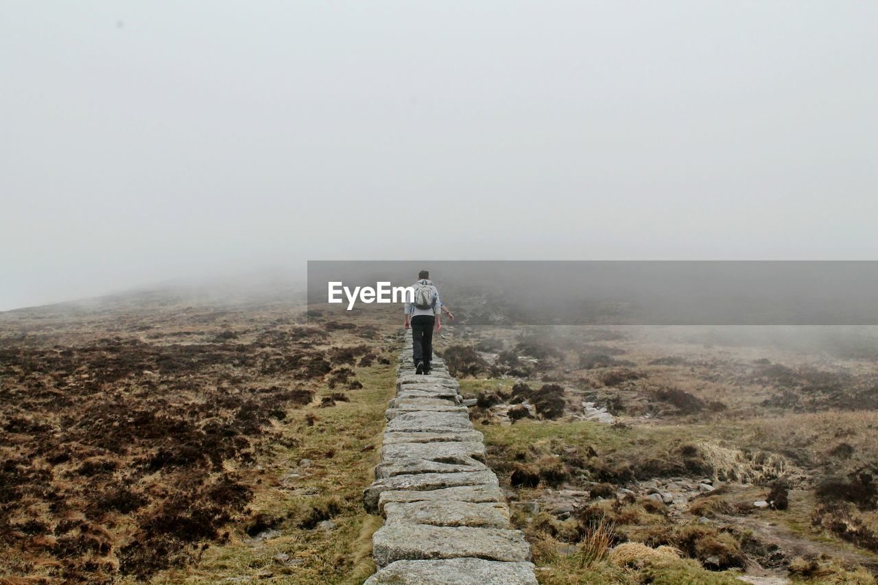 Rear view of man walking on stone walk