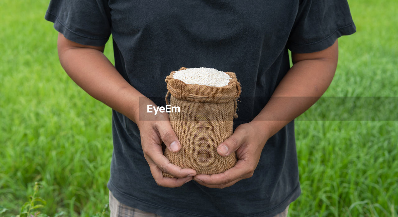 MIDSECTION OF MAN HOLDING HANDS ON FIELD