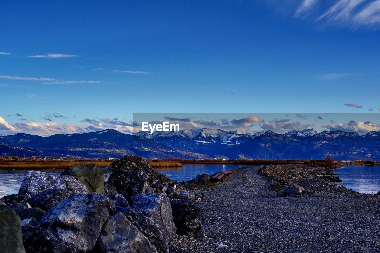 Scenic view of lake and mountains against blue sky