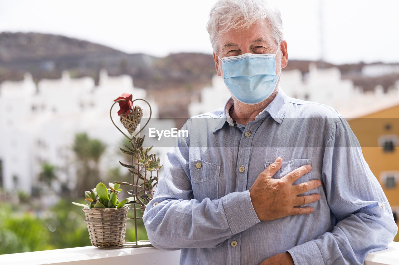 Portrait of senior man wearing mask standing outdoors