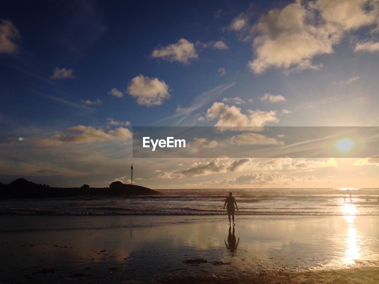 Person standing against sea during sunset