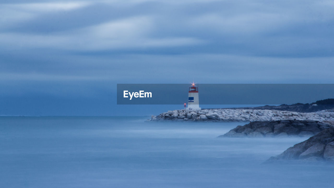 Lighthouse by sea against sky