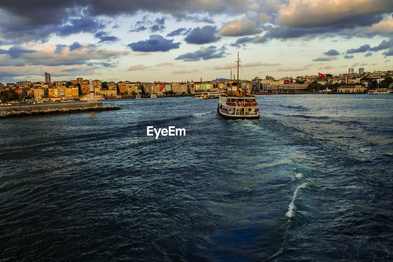 Ferry boat sailing in sea against cloudy sky