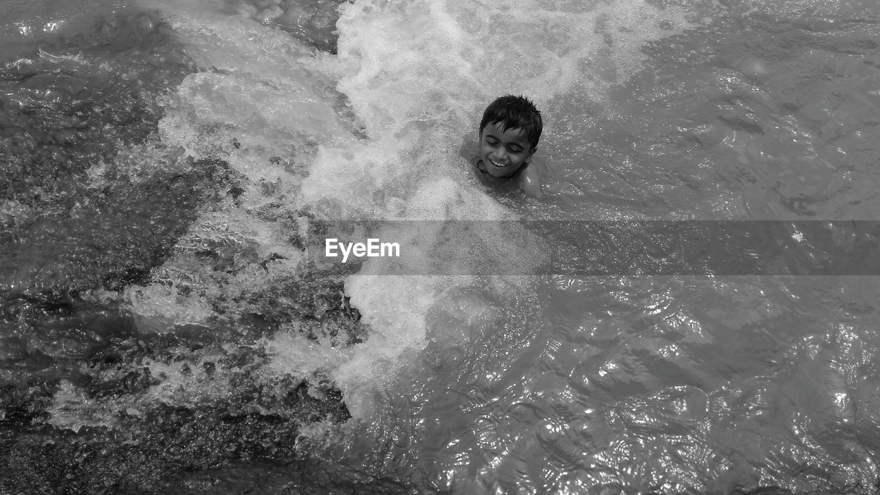 High angle view of smiling boy swimming in sea