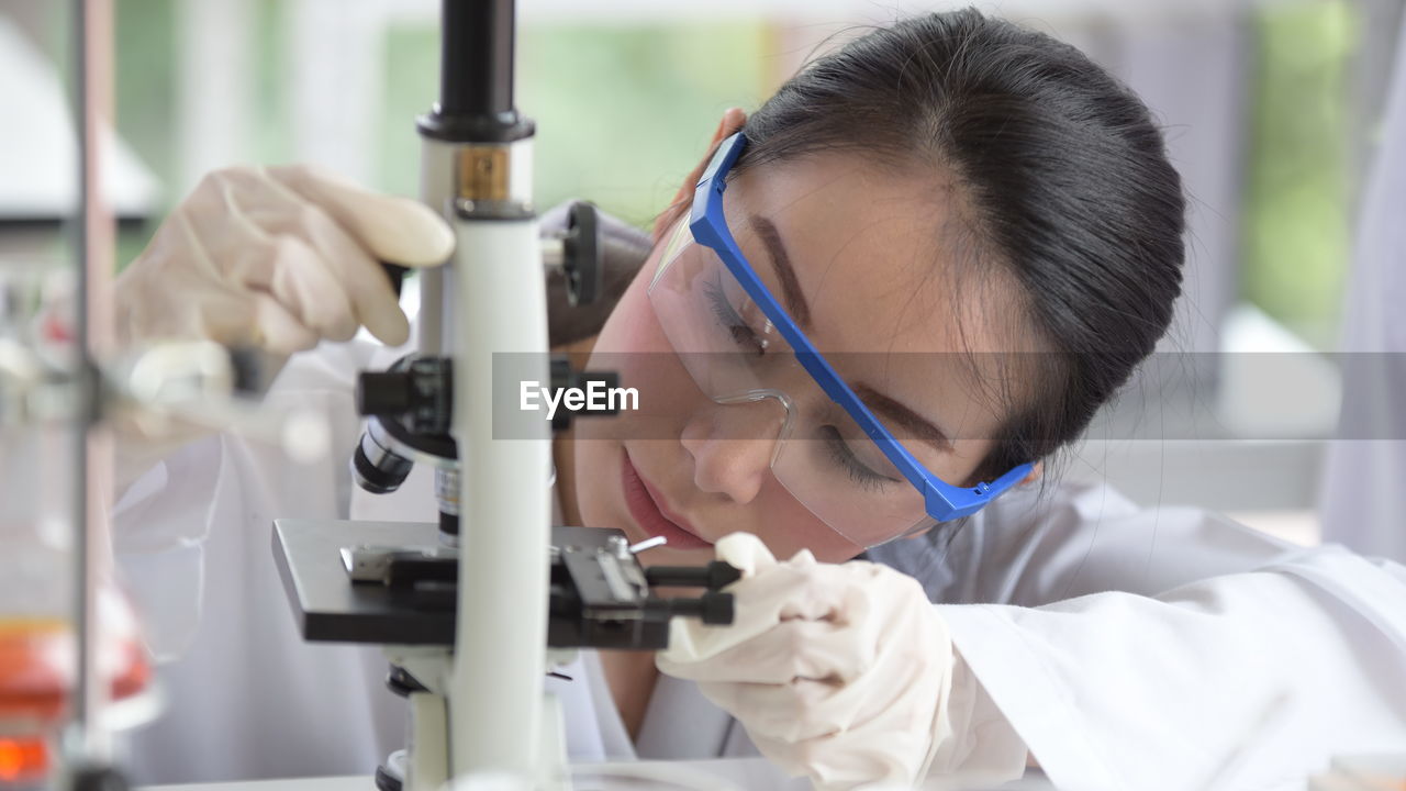 Scientist looking at microscope while sitting in laboratory