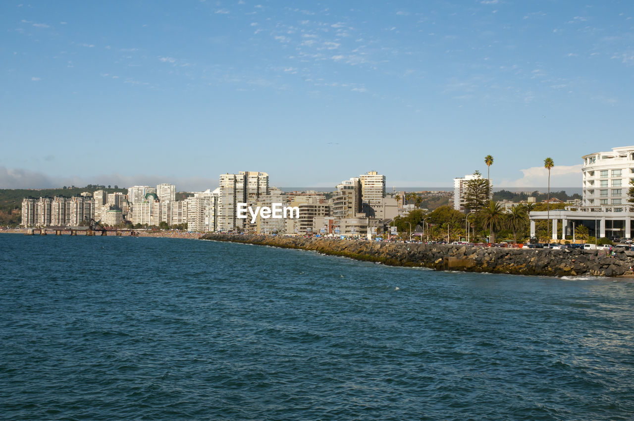 Sea by cityscape against sky