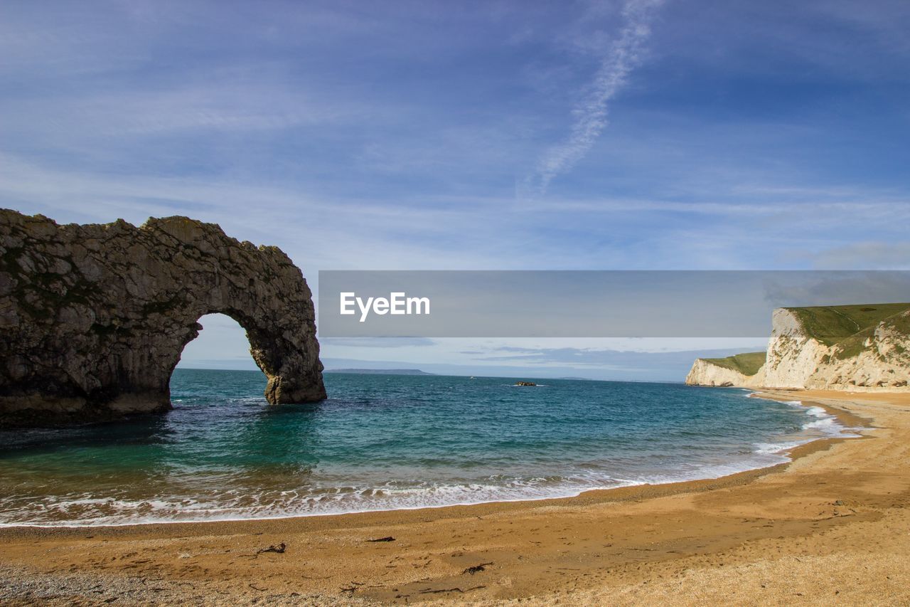 Rock formation on beach against sky