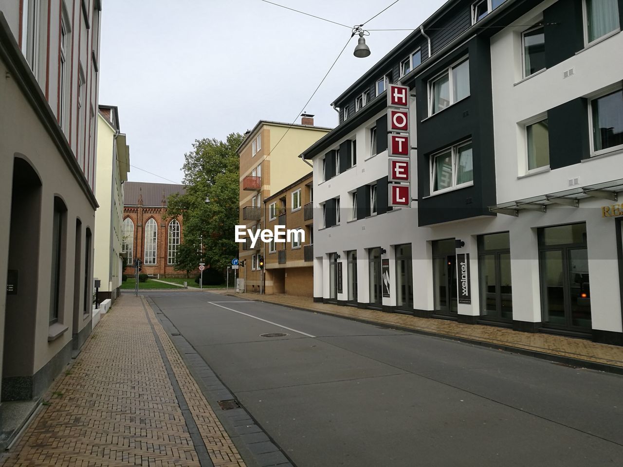 EMPTY ROAD BY BUILDINGS AGAINST SKY