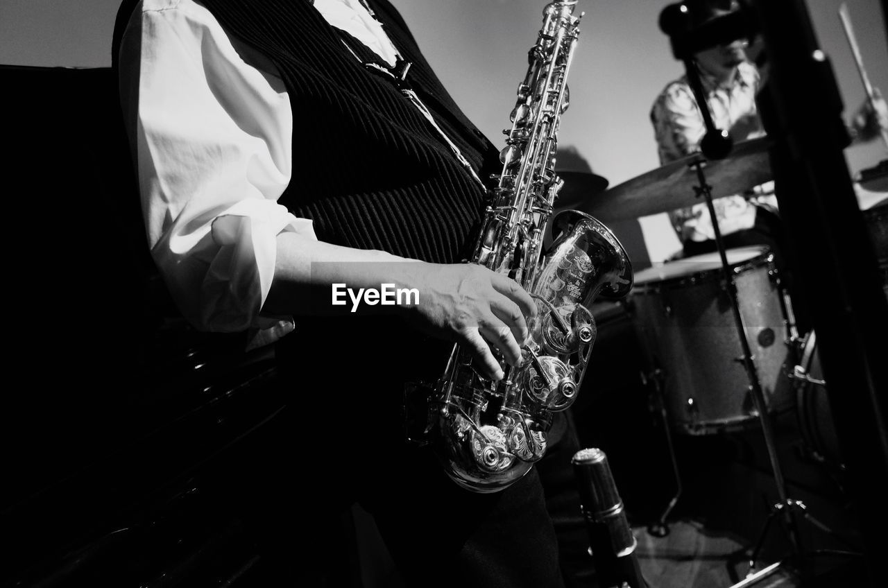 Midsection of man holding saxophone while standing in event