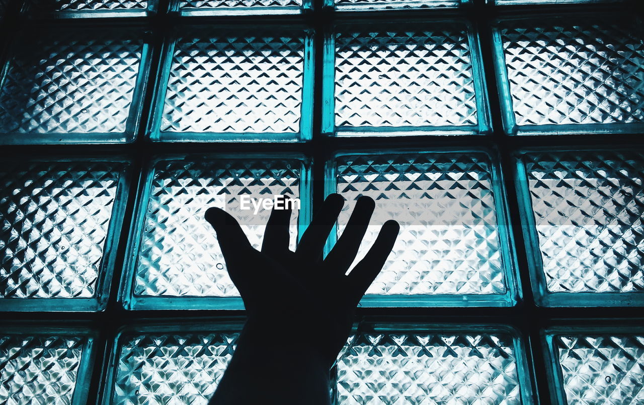Cropped image of hand against glass window
