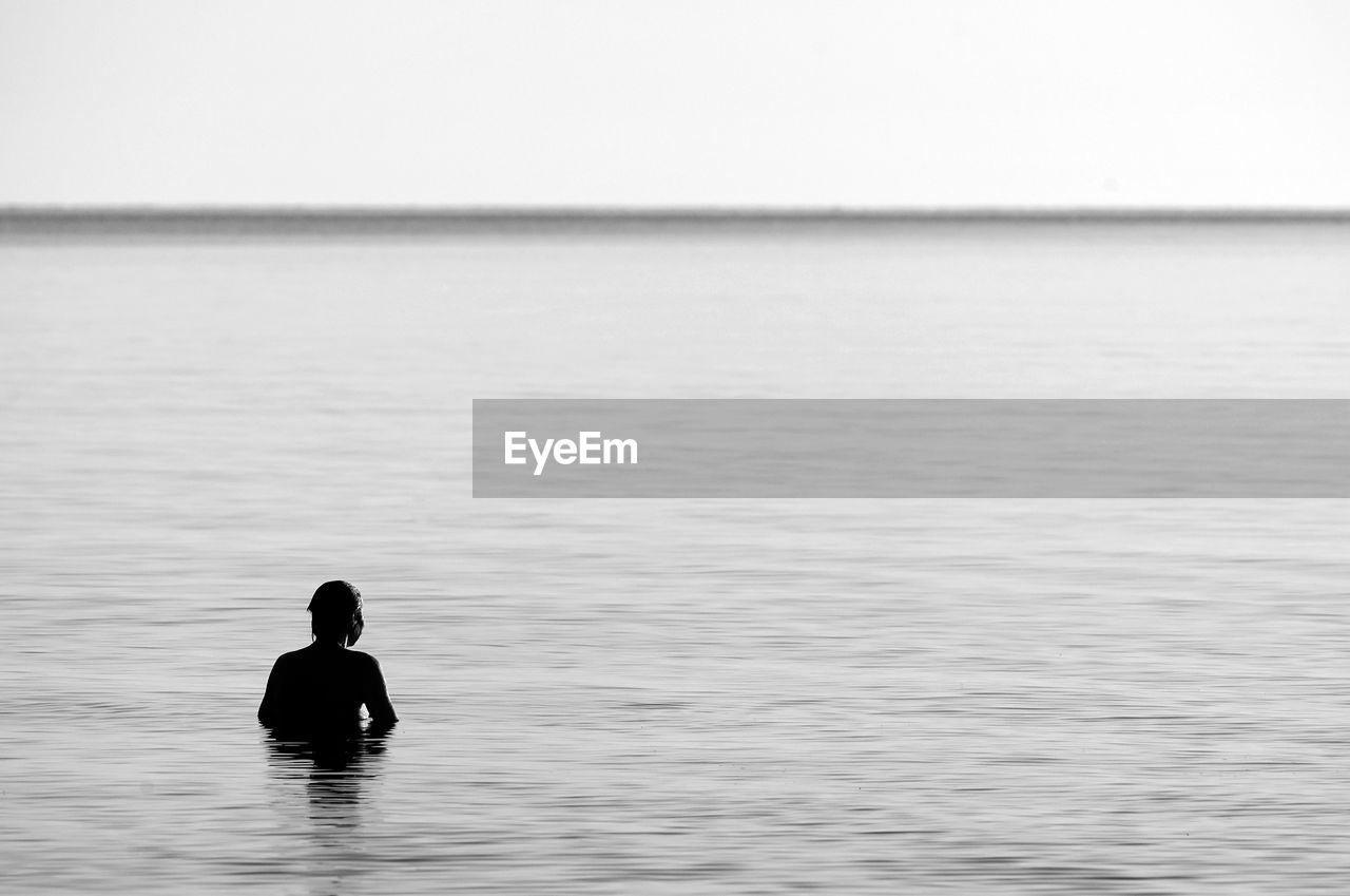 Rear view of silhouetted person in the sea