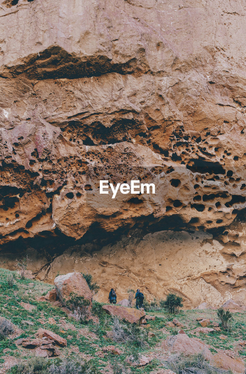 Low angle view of people hiking by rock formations