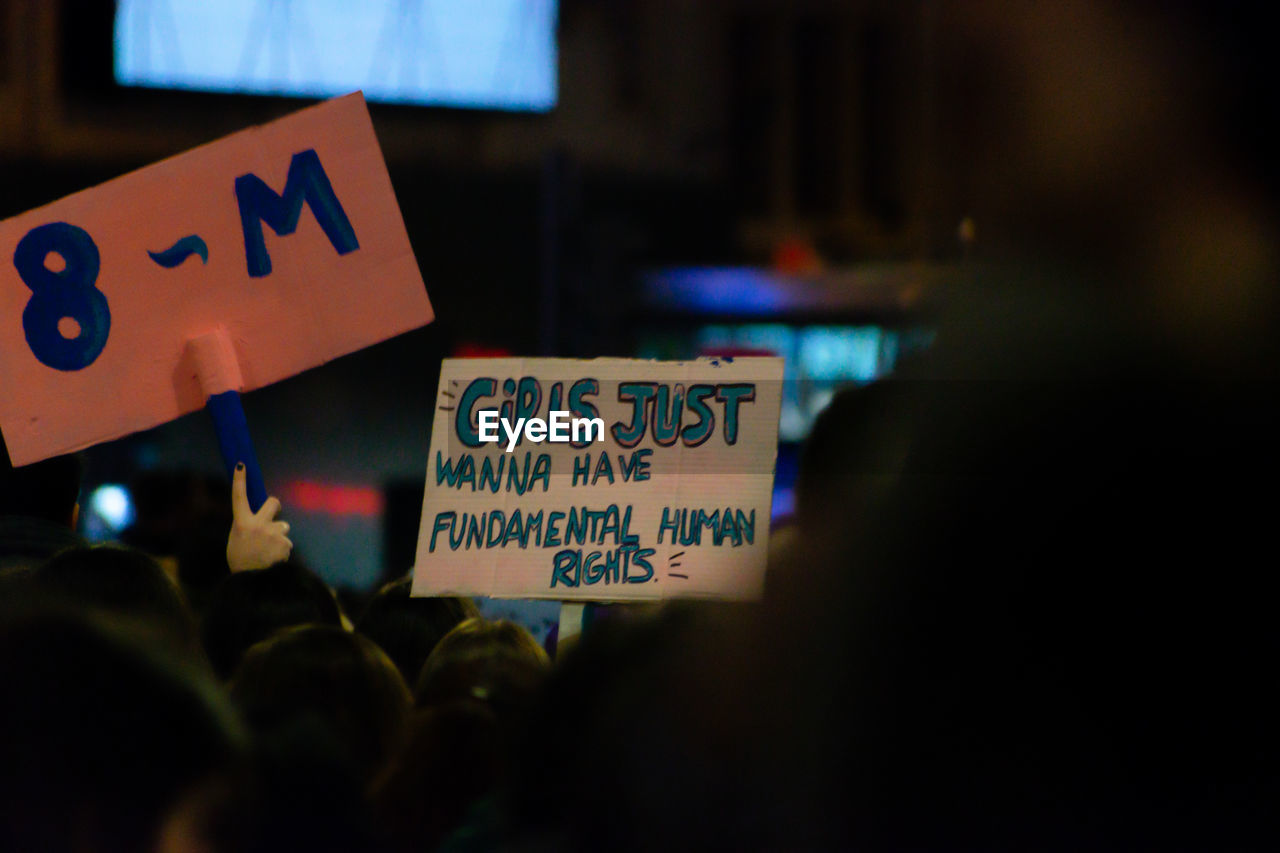 People holding placards with text during protest at night