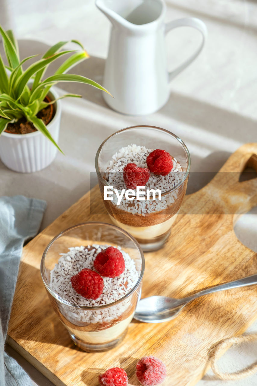 Three-layer mousse dessert made of chocolate and vanilla, decorated with fresh raspberries 