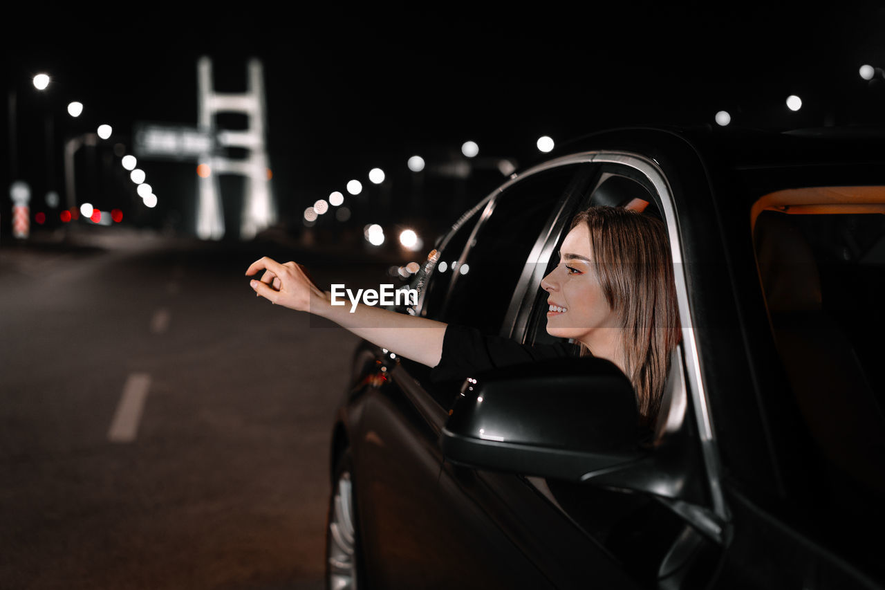 Portrait of beautiful young woman in car at night