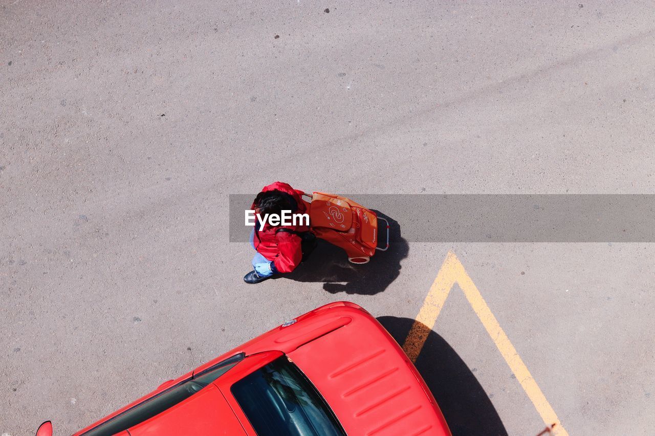 HIGH ANGLE VIEW OF MAN ON RED CAR