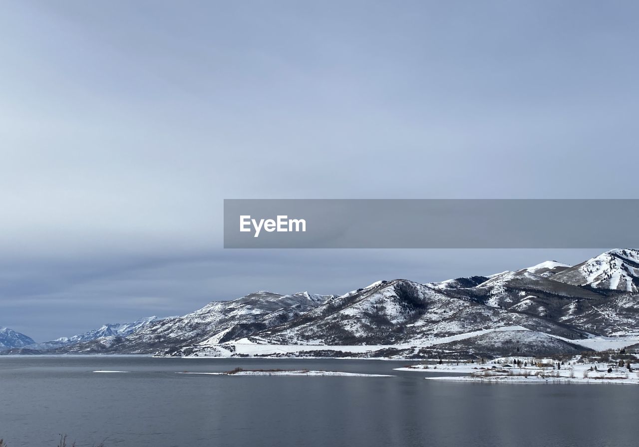 Scenic view of snowcapped mountains by sea against sky