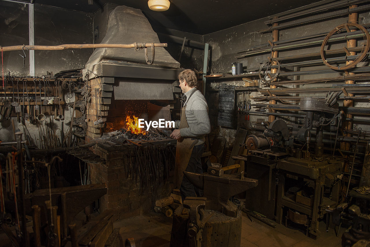 Blacksmith heating metal rod in fire