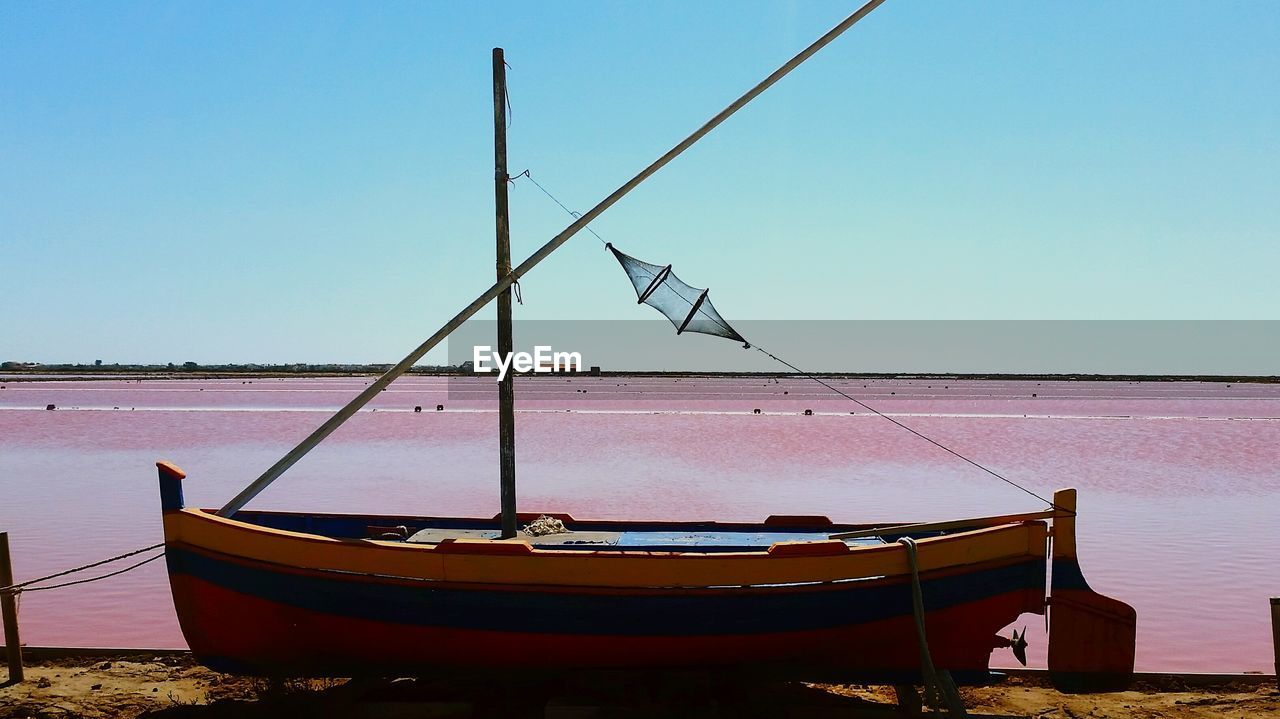 Ship moored on shore against clear sky