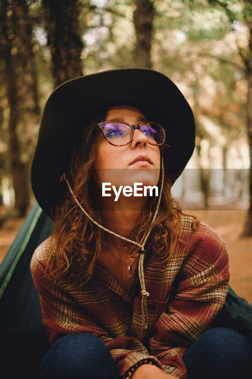 Young woman looking up sitting at forest