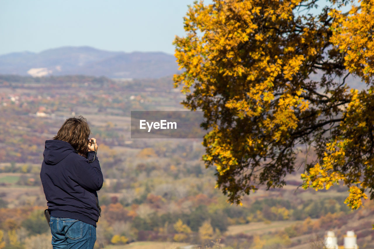 Rear view of man standing by tree on mountain