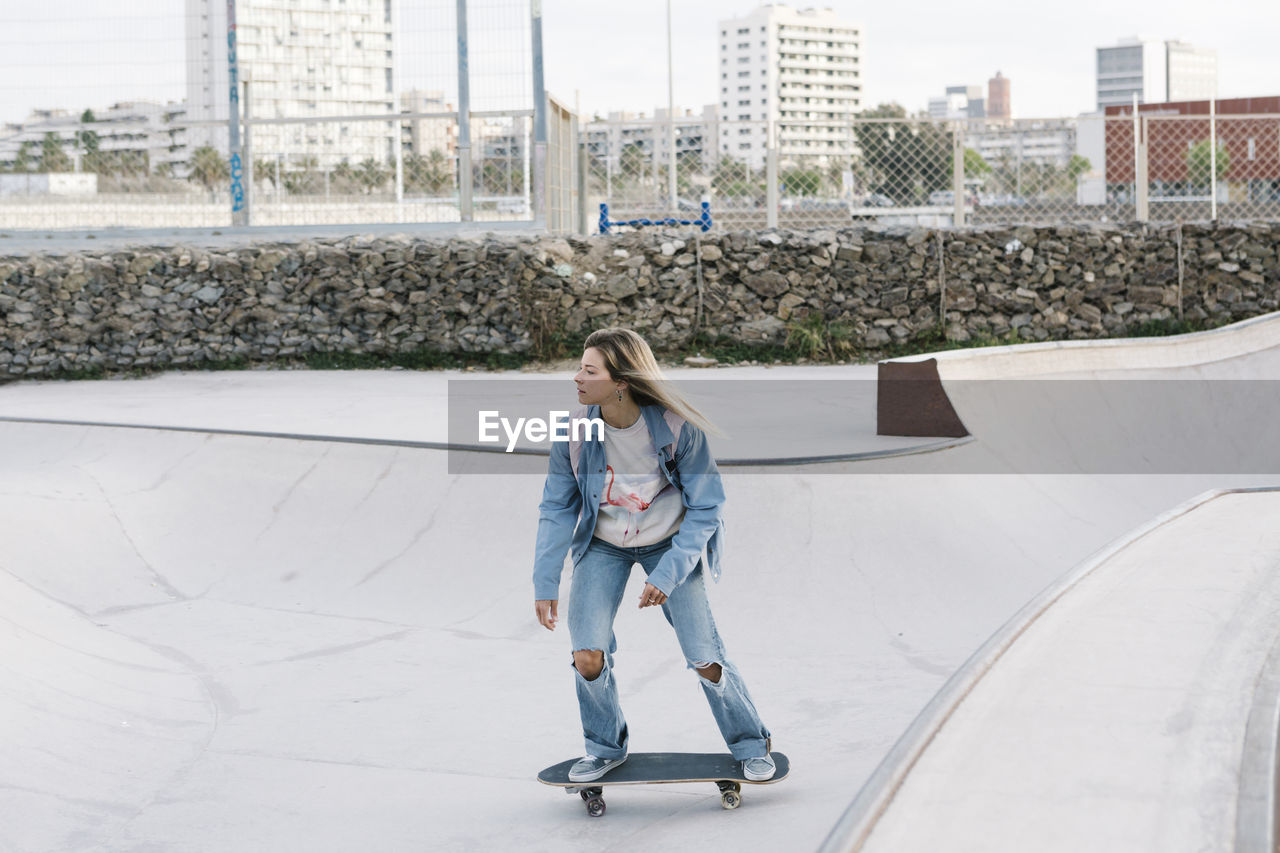 Mid adult woman looking away while riding skateboard in park