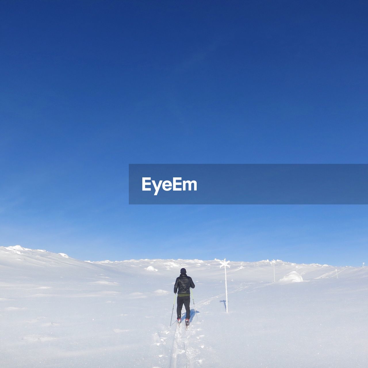 Rear view of man skiing on snow covered mountain against clear sky
