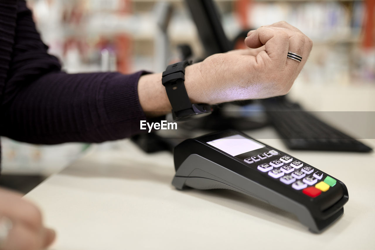 Man making contactless payment through smart watch at checkout counter in store