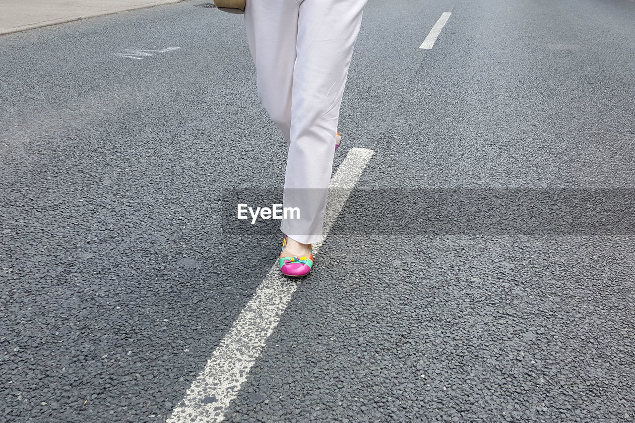 Low section of woman walking on road