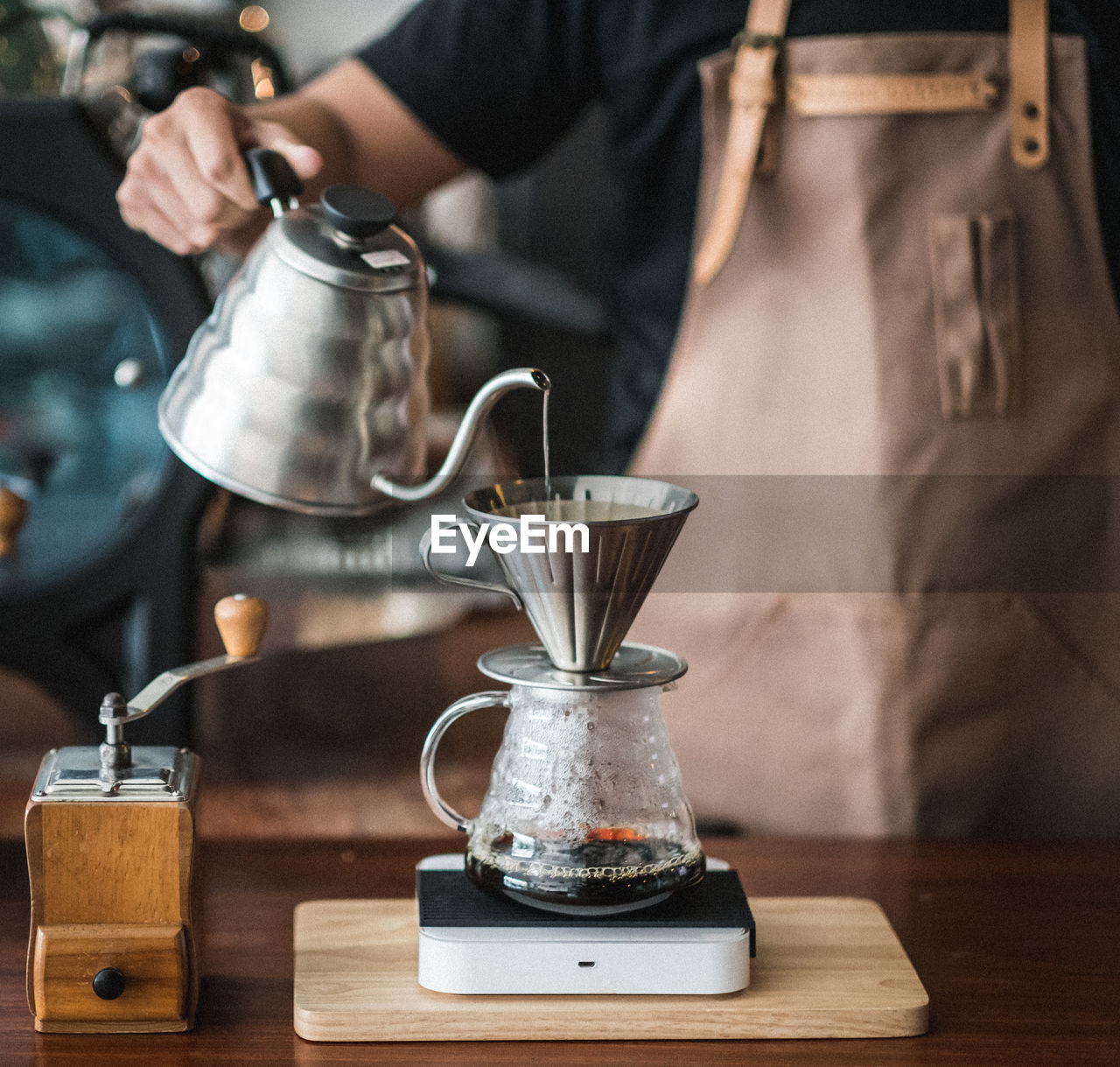 Midsection of barista pouring coffee in jar on table