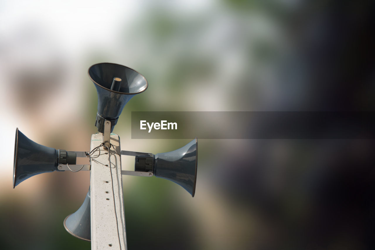 Low angle view of megaphones on metallic tower against blurred background