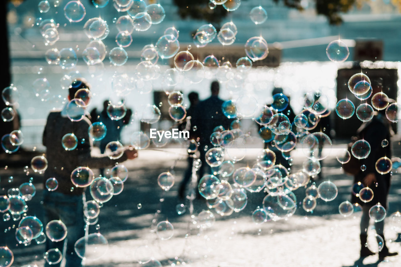 Bubbles and people on footpath during sunny day