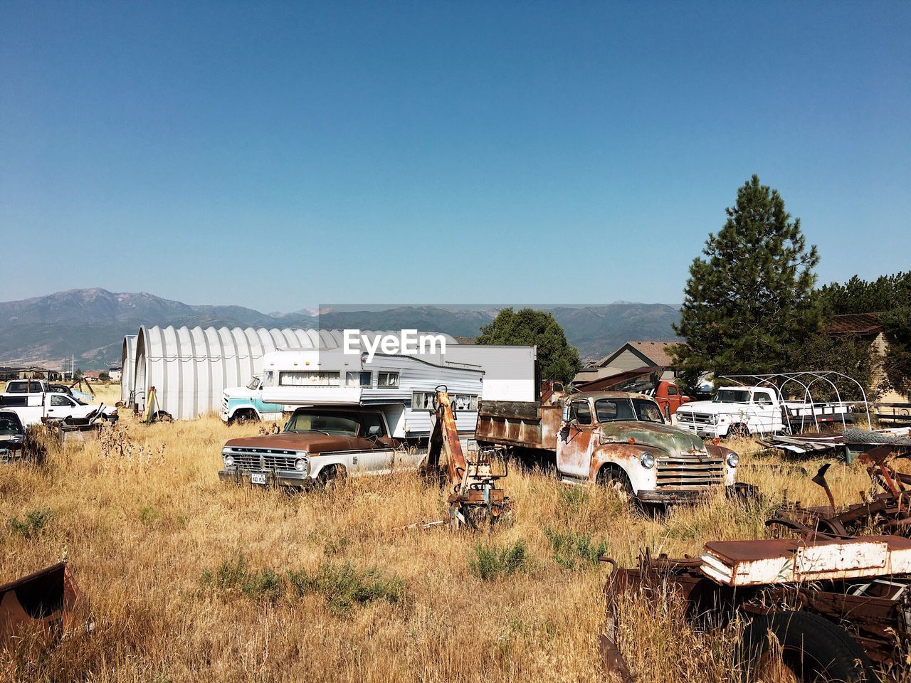 ABANDONED CARS ON FIELD AGAINST SKY