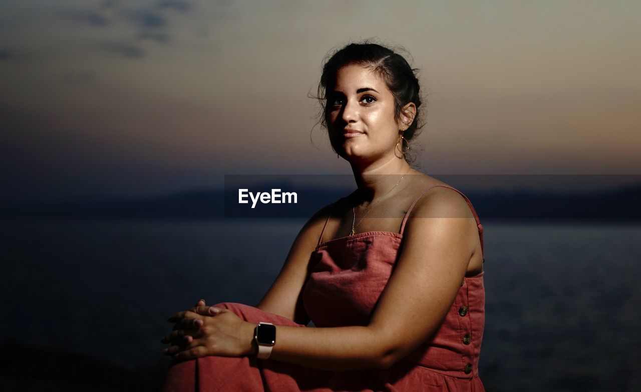 Portrait of woman standing against sea at sunset