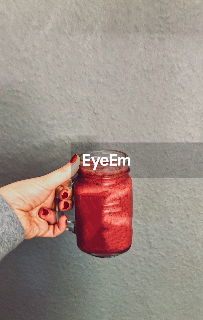 Cropped hand of woman holding smoothie in jar