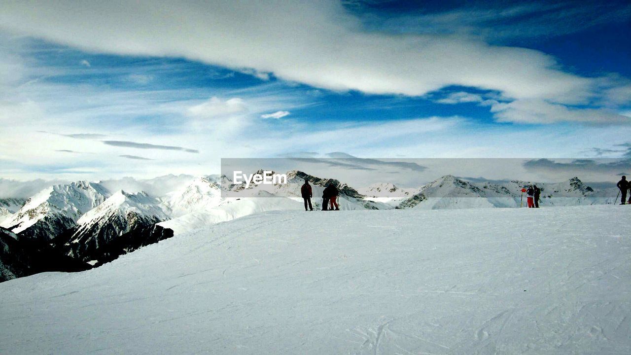 PEOPLE WALKING ON SNOWCAPPED MOUNTAIN AGAINST SKY