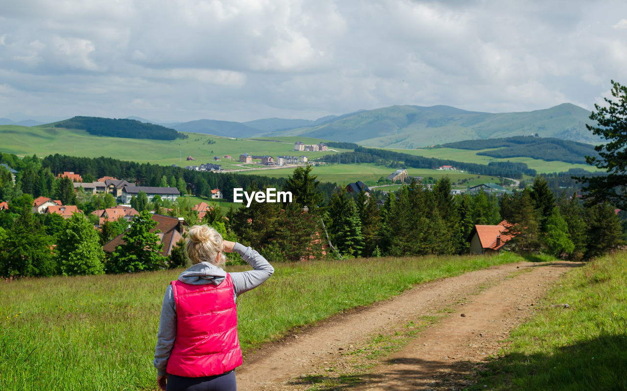 Blond woman watching and enjoying a mountain landscape in springtime