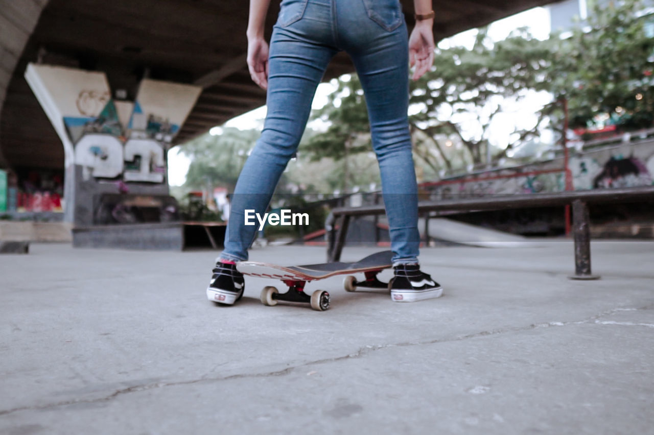 LOW SECTION OF MAN WITH SKATEBOARD ON STREET