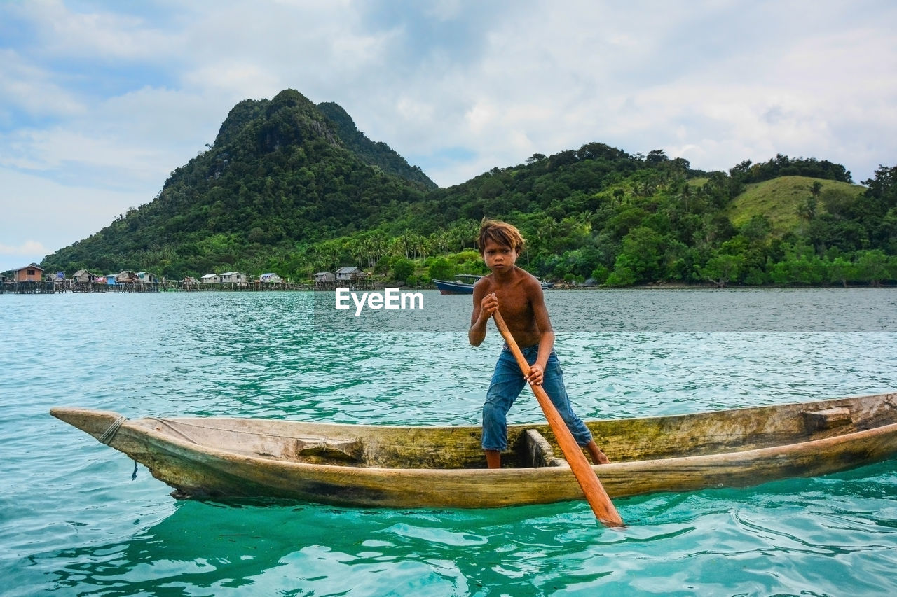 FULL LENGTH OF SHIRTLESS MAN IN BOAT